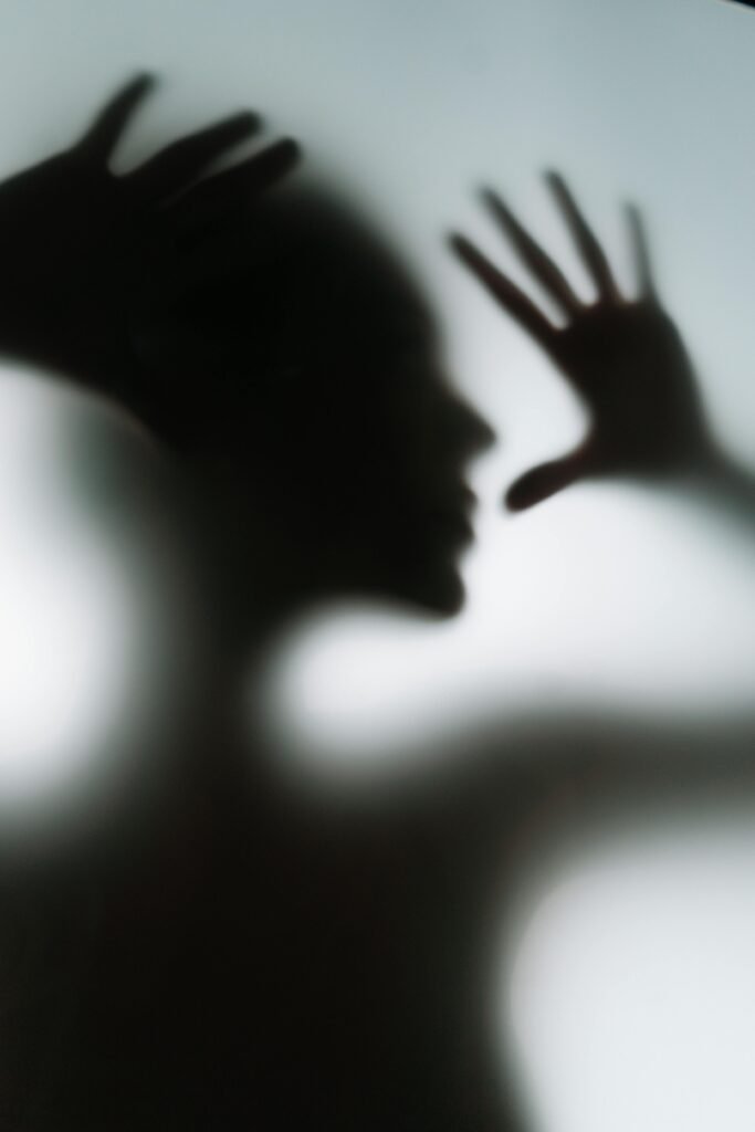 Silhouette of a human figure behind frosted glass creating a mysterious and eerie ambiance.