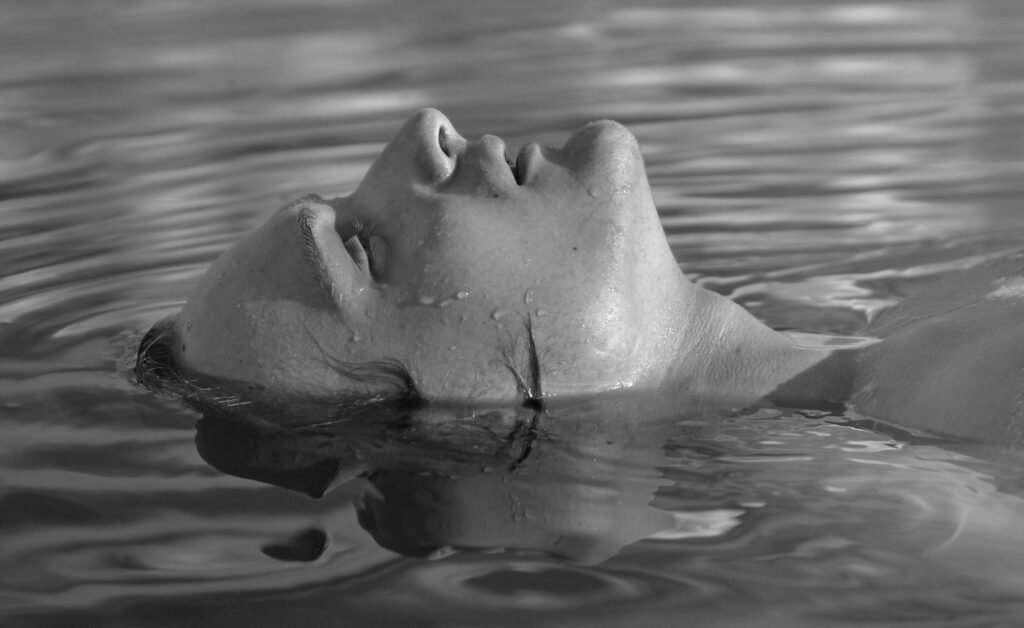 Black and white portrait of an adult woman floating peacefully in water.